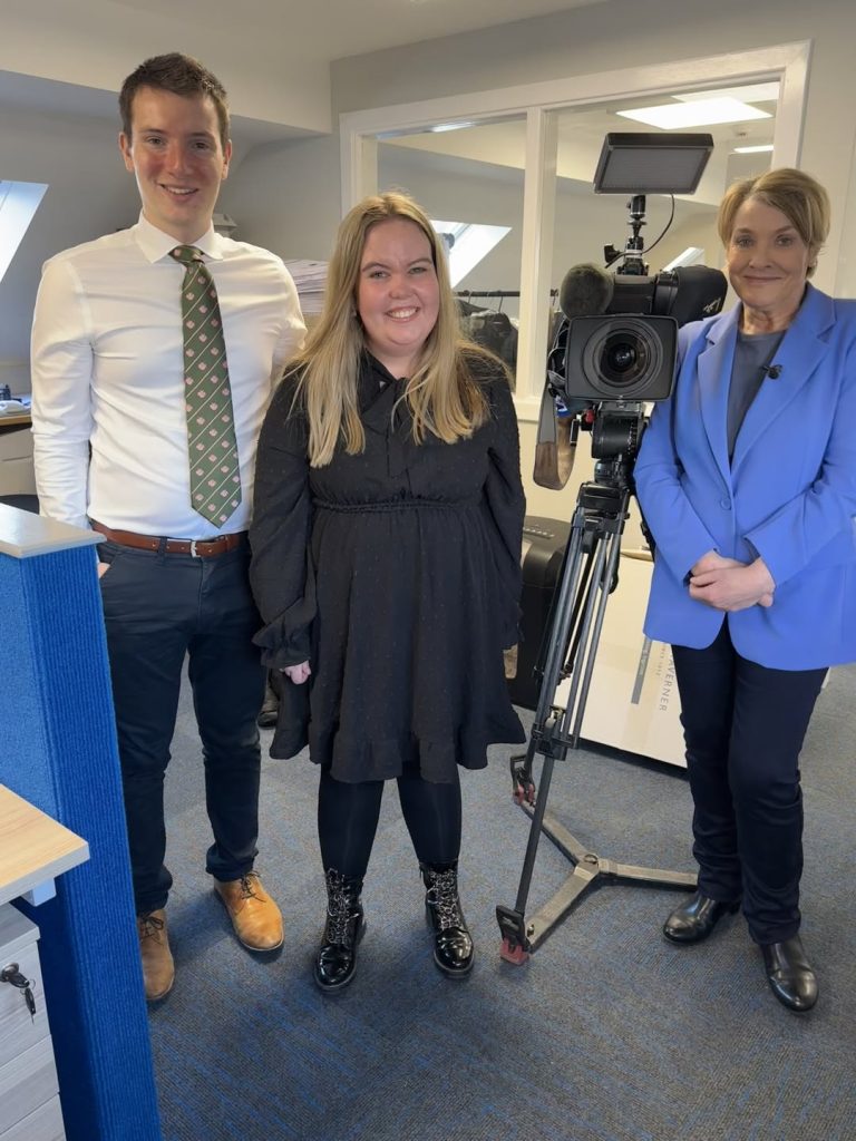 Young woman (Skye) stands in the middle, between Cairndale Hotel owner (Matthew Wallace) and ITV Broadcaster Fiona Armstrong.
