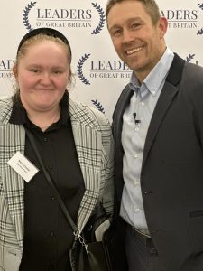 Young woman stands next to international rugby star Jonny Wilkinson with logos behind for Leaders of Great Britain