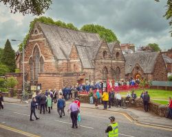 Photo of the outside of The Usual Place building with many people walking towards it and queuing to get in for a special event