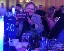 Young woman at awards dinner table holding up winners certificate