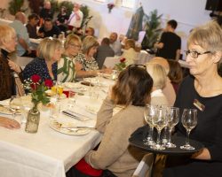 Between courses a chance to catch up and chat with other guests Guests sit at the tables between courses chatting and smiling.