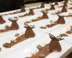 Chocolate, Hazelnut and PX Sherry Mousse, Candied Pecans,
Mascarpone Ice Cream White rectangular plates all lined up with identical deserts including chocolate sauce, mouse, chocolate butterfly and candied pecans
