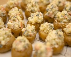 Canapes: Whisky Smoked Salmon and Potato Salad A close up image of tiny potatoes on a plate each is stuffed iwth a whisky smoken salmon salad.